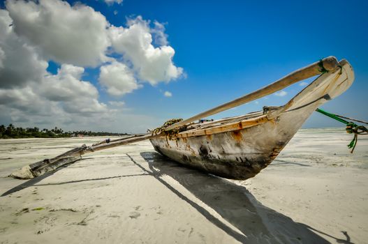 Zanzibar catamaran fishing boat on sand beach in summer with some clouds on the sky