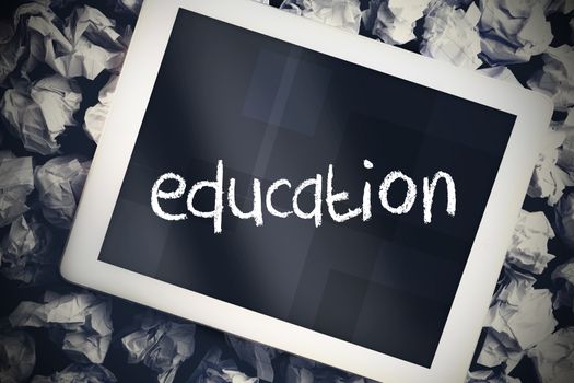 The word education in search bar on tablet screen on crumpled papers