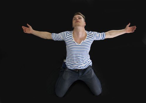 Handsome blond young man with arms spread open, isolated on black