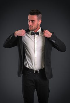 Attractive young businessman with suit and bowtie, on dark background