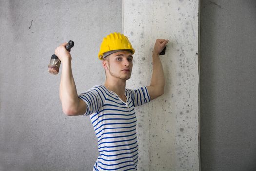Handsome construction worker with yellow hard hat and hammer in hand
