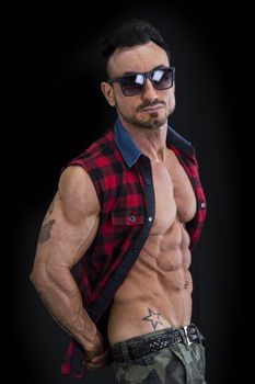 Profile shot of muscular young man in military pants and open shirt on naked torso