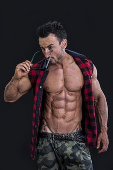 Frontal shot of muscular young man in military pants and open shirt on naked torso