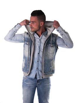 Handsome young man in hoodie, denim vest and jeans, isolated on white