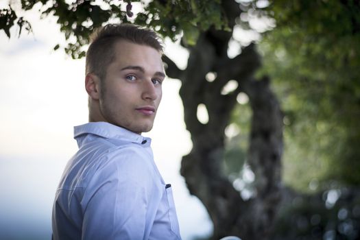 Profile shot of handsome young man outdoors looking at camera