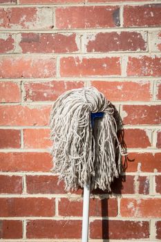 the new mop as still life on the brick wall