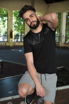 Handsome young man with beard, wearing t-shirt and shorts, looking at camera