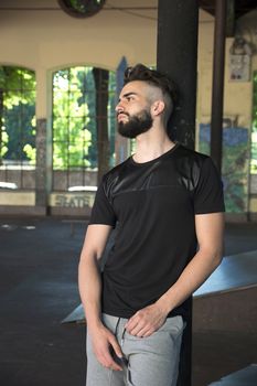 Handsome young man with beard leaning against black pole