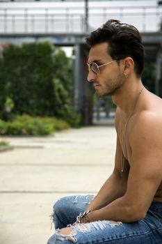 Handsome shirtless man outdoor in urban environment, profile shot