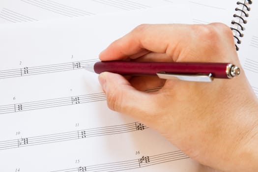 Hand with pen and music sheet, musical background