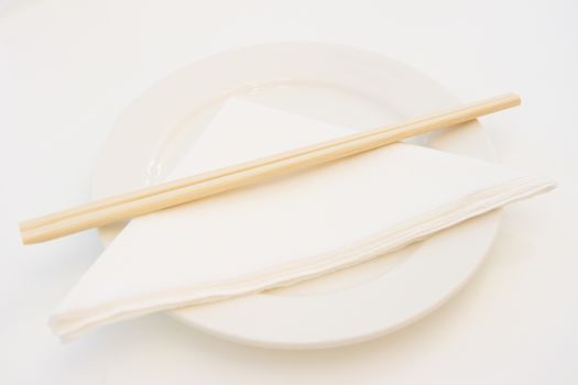 White plate with wooden chopsticks and paper napkin on, shallow depth of field