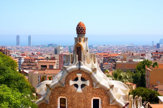 Detail of Casa del Guarda (lodge) in Park Guell (1900-1914) of Barcelona - Spain. Architect Antoni Gaudi (1852-1926) and panorama of the city