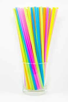 Front view of colorful drinking straws in glass isolated on white background