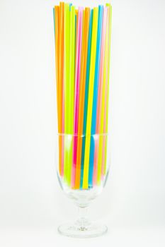 Front view of colorful drinking straws in glass isolated on white background