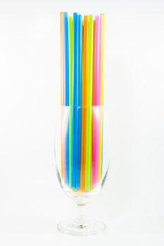 Front view of colorful drinking straws in glass isolated on white background