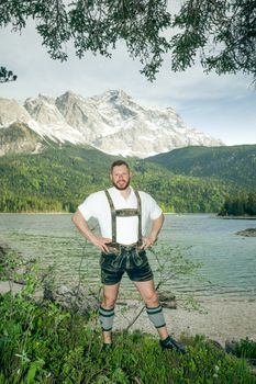 A traditional bavarian man at lake Eibsee with the Zugspitze mountain in the background