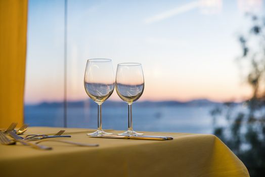 Two wine glasses against a sea and mountains