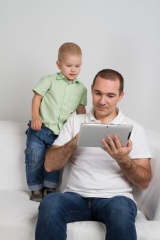 Dad and son watching the tablet sitting on the couch