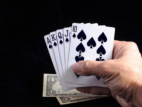 Flush royal cards on hand with money  isolated on black background 