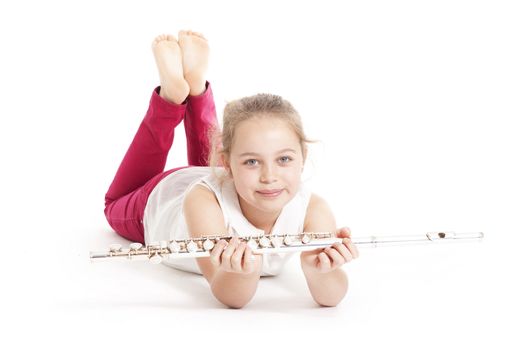 young  girl holding flute lying on the floor of studio with white background