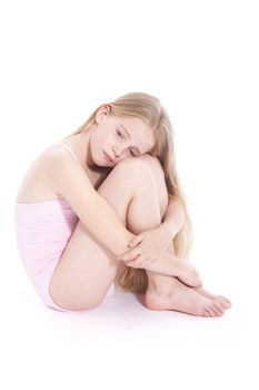 young girl in pink with sad expression sitting on floor of studio against white background