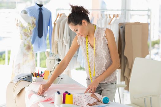 Concentrated young female fashion designer working on fabrics in the studio