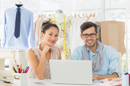 Male and female fashion designers using laptop at work in a studio