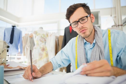 Young male fashion designer working on his designs in the studio