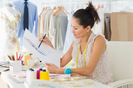 Side view of a young female fashion designer working on her designs in the studio