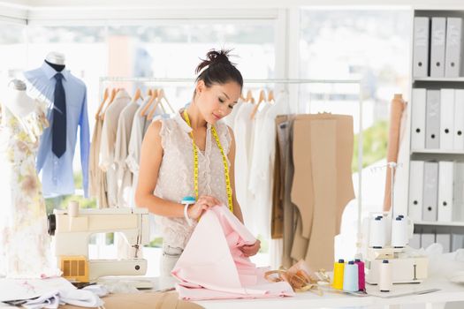 Concentrated young female fashion designer at work in a studio