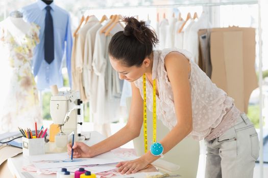 Side view of a young female fashion designer working on her designs in the studio