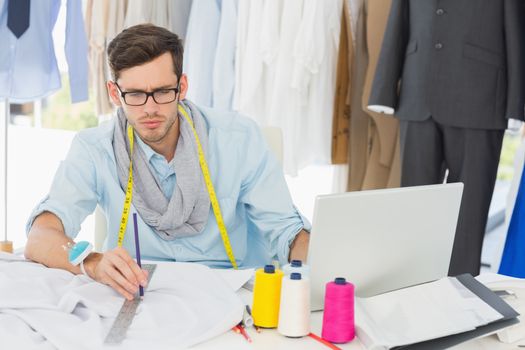 Young male fashion designer working on his designs in the studio