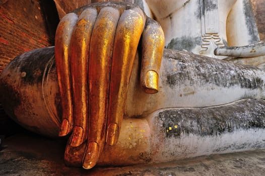 gold leaf offerings on slender fingers of wat si chums iconic big buddha statue in sukhothai historic park northern thailand