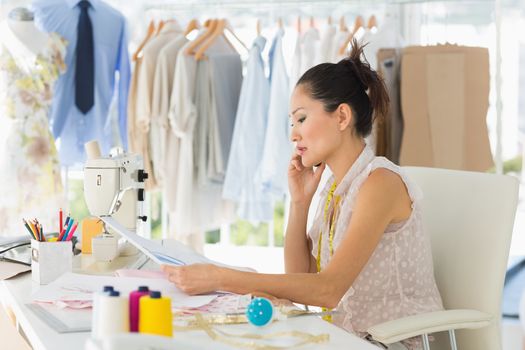 Side view of a young female fashion designer working on her designs in the studio