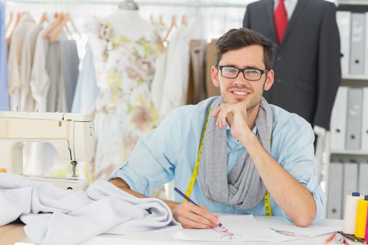 Young male fashion designer working on his designs in the studio