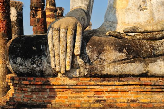 gold leaf offerings on slender fingers of wat si chums iconic big buddha statue in sukhothai historic park northern thailand