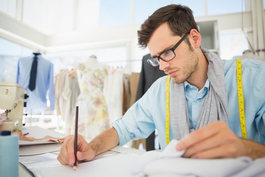 Young male fashion designer working on his designs in the studio