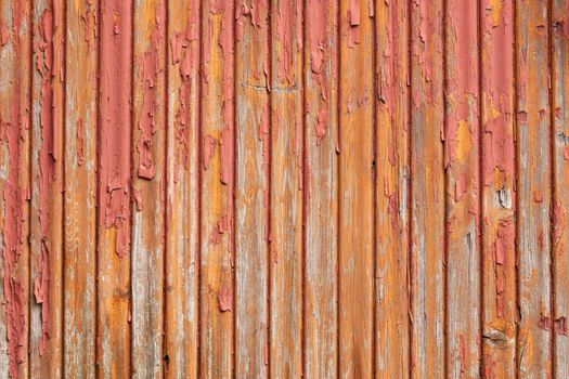 horizontal picture of old grey vertical planks with fading red and orange paint