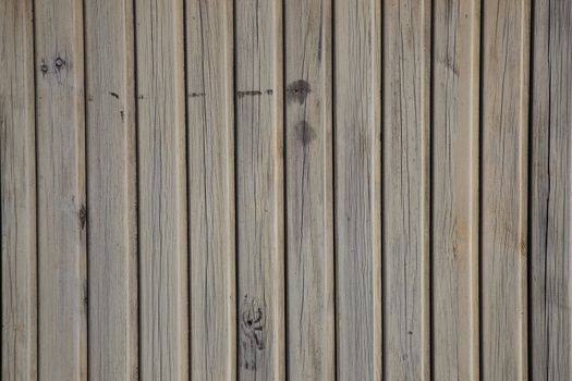 horizontal picture of old grey vertical planks with peeling beige and brown paint