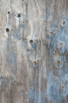 grey wooden board with knots and remnants of blue paint