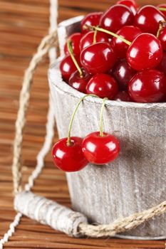 Fresh cherries with water drops in a wood bucket