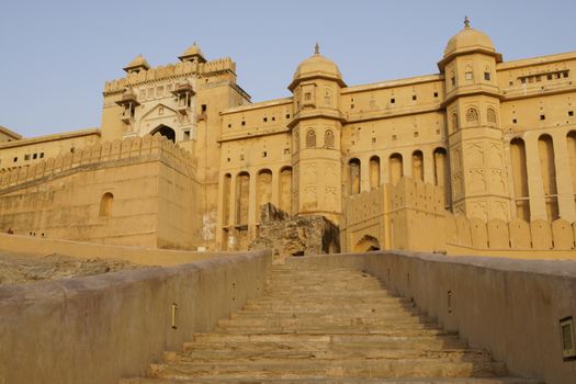 Steps leading up to the imposing front entrance (Suraj Pol) to Amber Fort. Large honey coloured Moghul style building. Jaipur, Rajasthan, India