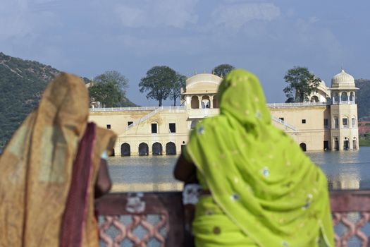 Indian ladies in colorful sari's look out over the Water Palace (Jal Mahal) in the middle of Man Sagar lake. Jaipur, Rajasthan, India. 18th Century