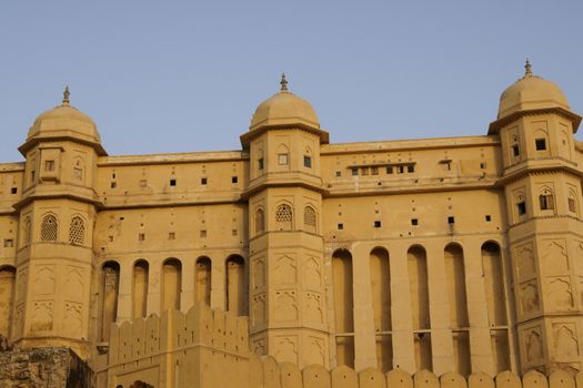 Imposing walls of Amber Fort. Large honey coloured Moghul style building. Jaipur, Rajasthan, India