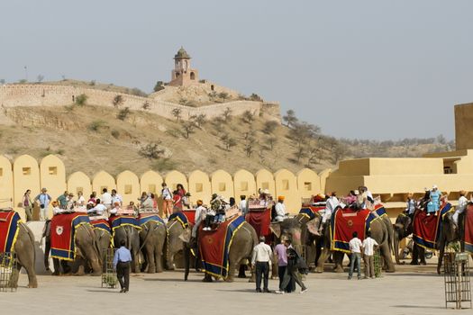 Tourists dismount from elephants in the courtyard of Amber Fort. Elephants are used at Amber Fort to transport tourists up a hill from the road to the courtyard inside the fort.