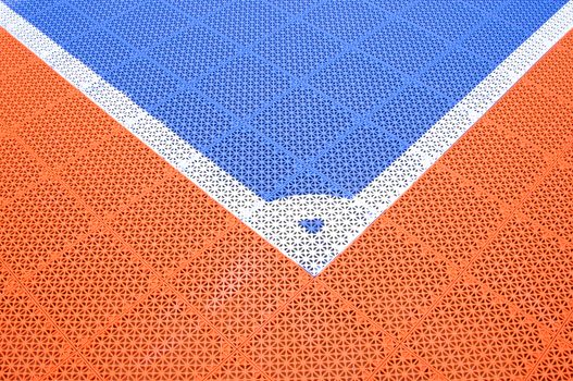 Corner of blue plastic soccer field with orange and white.