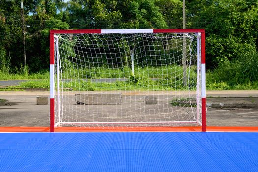 Red and white goal of blue and orange soccer field.