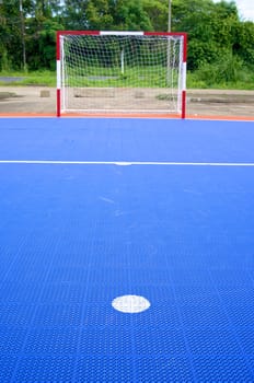 Point of penalty in front of blue soccer field with red and white goal.