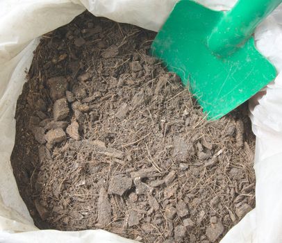 Soil and spathe coconut with green trowel in plastic bag.