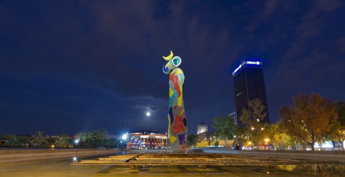BARCELONA, SPAIN - JUN 12, 2014: Dona i Ocell (Woman and Bird) of Joan Miro (1893-1983) realized by ‪Joan Gardy Artigas‬ (1983) at night in the Park Joan Miro. In the background the Bullring Arenas